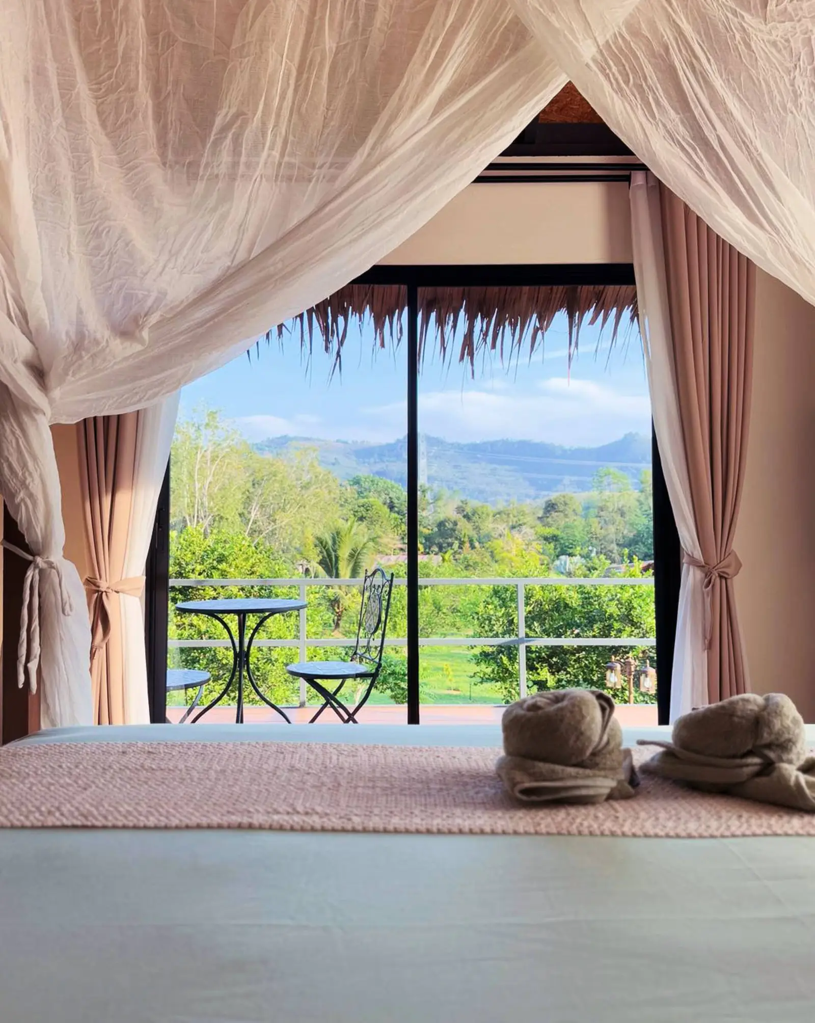 Canopy bed curtains opening onto the balcony and mountains